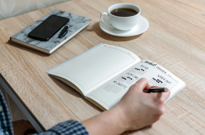 Notebook habit tracker showing simple challenges for motivation through small daily actions.