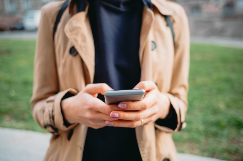 Woman typing ideas on a phone outdoors to show how to capture ideas before they disappear.