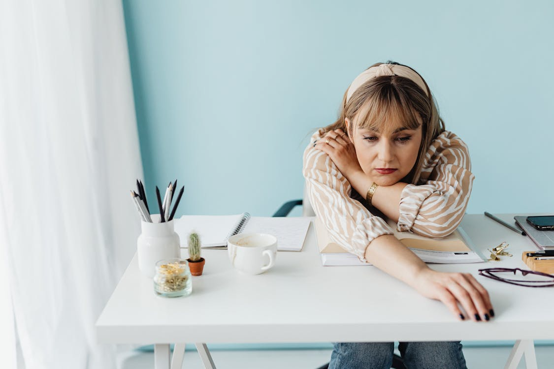 Woman sitting at a desk looking mentally drained as a sign you’re stuck in a routine.