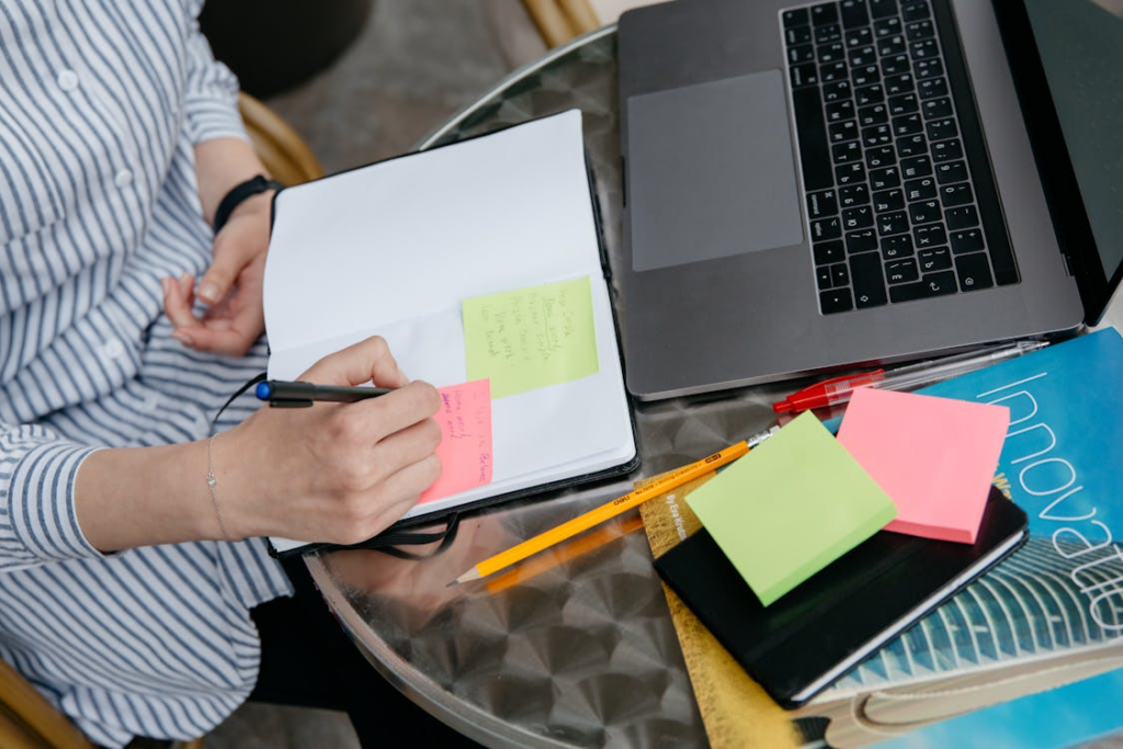 Person using sticky notes and a notebook for creative thinking exercises that build fresh ideas.