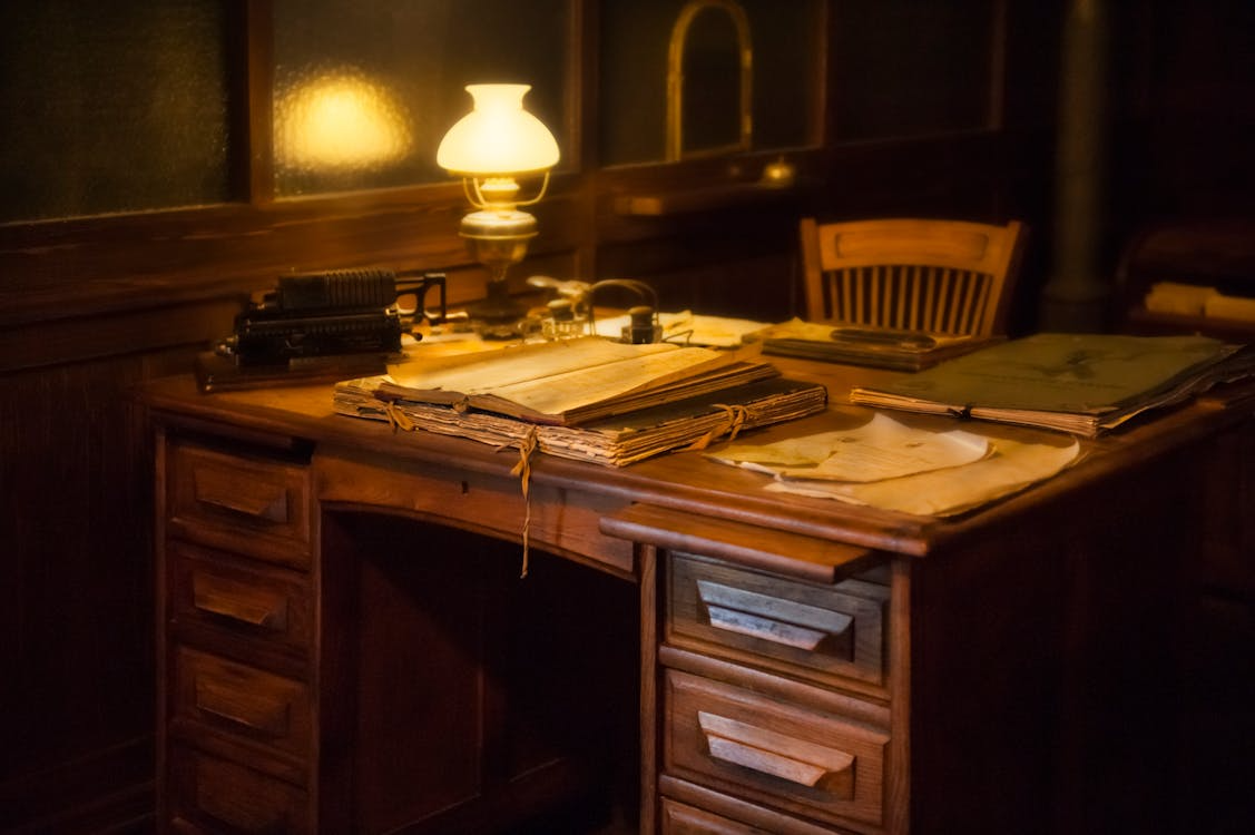 Vintage desk with old notes and books showing the habits of creative thinkers through reflection.