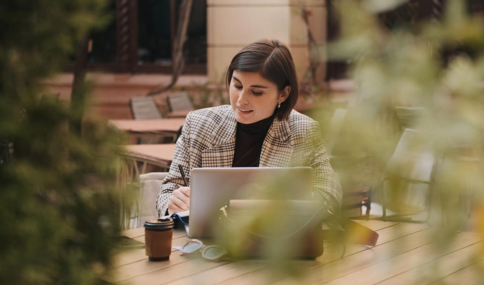 Woman working outdoors with a laptop showing how environment affects thinking and focus.