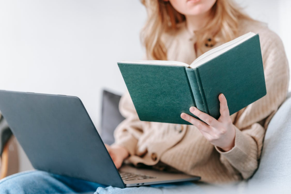 Woman reading with a laptop nearby showing how curiosity improves life through lifelong learning.