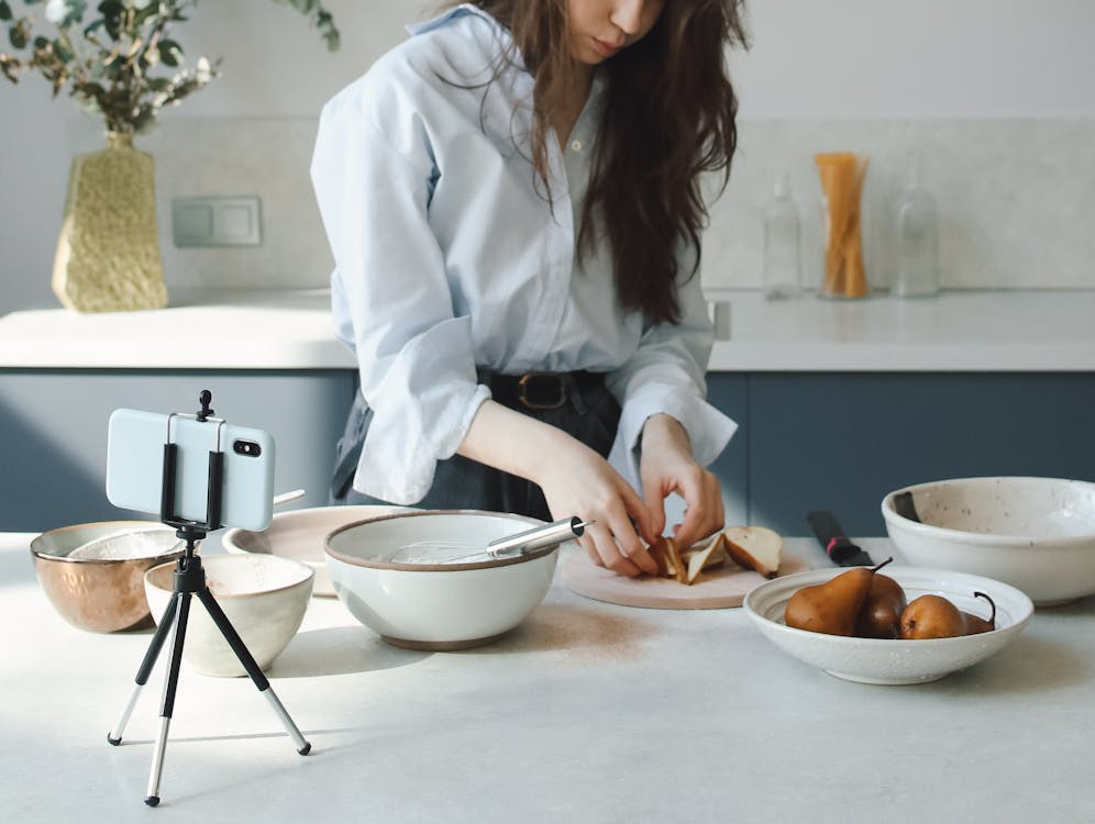 Woman filming a simple cooking project as one of the affordable hobbies to start at home.